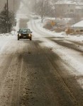 17357046 a small car drives down a deserted city street during the season s first snow storm in denver colora
