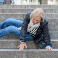 an older woman lying awkwardly on stairs after a fall