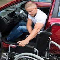 man uses wheelchair to exit vehicle