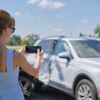 woman takes photo of car after collision